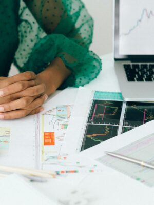 A person analyzes financial charts and graphs at a desk, indicating business trading activity.