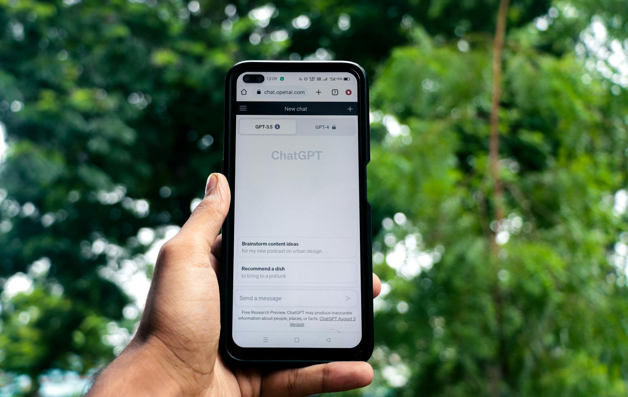 Close-up of a hand holding a smartphone displaying ChatGPT outdoors.