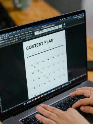 Close-up of hands typing on a laptop displaying a content plan document, ideal for business or marketing content.
